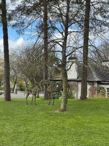 wooden animal sculptures on a lawn near a country house