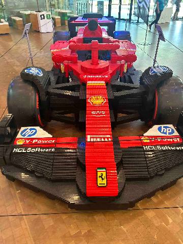 a life-size model race car made of plastic building blocks inside a building