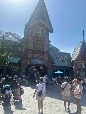 a clock tower entrance in a themed outdoor public square with visitors
