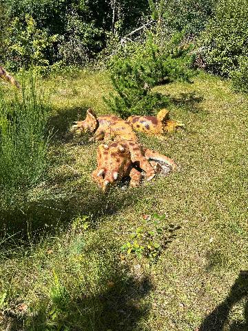 three dinosaur statues in a grassy park setting