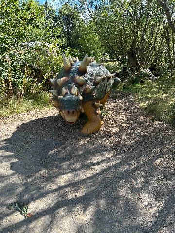 a dinosaur model on a woodland path