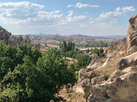 Goreme, Goereme — a high-angle landscape view of rock formations, trees, and a town in the distance