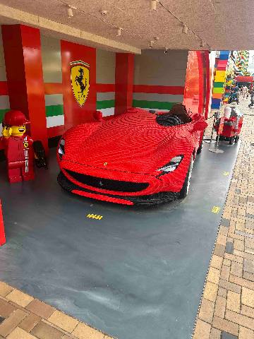 a large plastic brick model of a sports car at a themed attraction