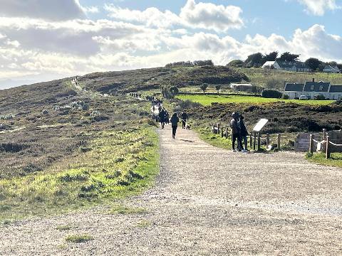 a walking path through a coastal landscape with people and houses