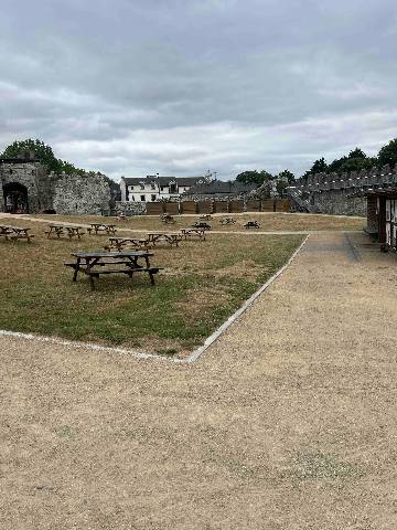 A courtyard with picnic tables and stone walls.