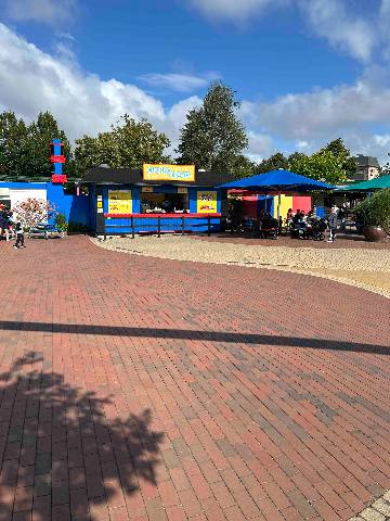 A blue food kiosk and seating area in an amusement park.