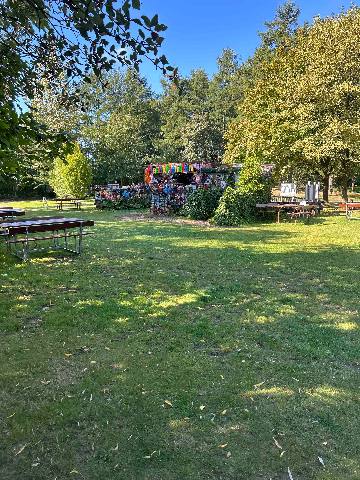 a park area with picnic tables and a decorated structure in a wooded setting