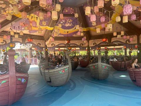 an amusement park teacup-style boat ride with hanging lanterns