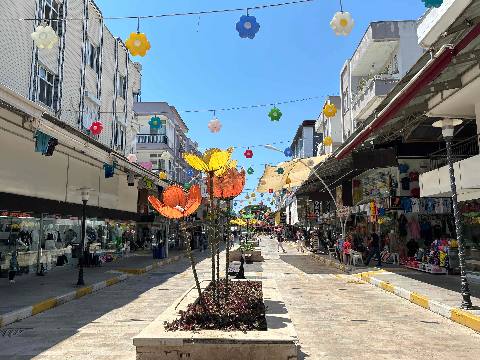 Belek, a pedestrian street with shops, hanging flower decorations, and artificial flower sculptures