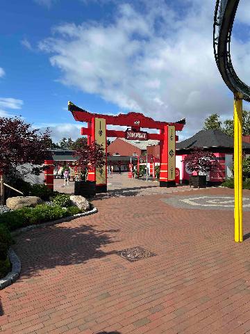 a theme park entrance with a red gate at a park