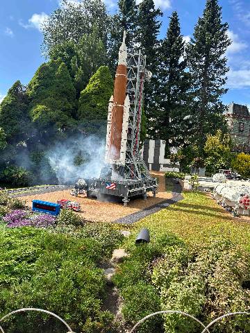 a miniature model rocket display in an outdoor garden setting